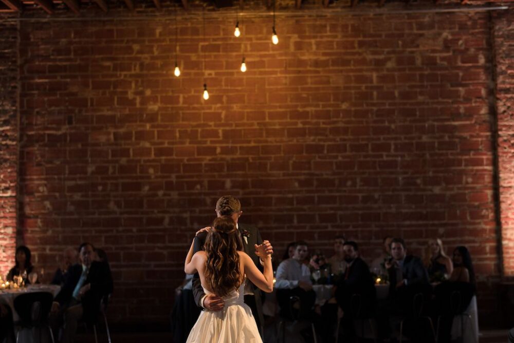 Wedding Reception First Dance Portrait with Exposed Brick Wall and Hanging Edison Bulb Lights | Unique Downtown St Pete Wedding Venue NOVA 535
