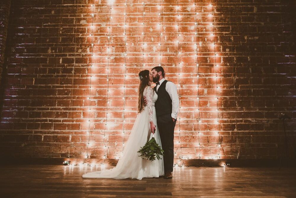 Modern string light ceremony backdrop in front of exposed brick wall at St. Pete wedding venue Nova 535