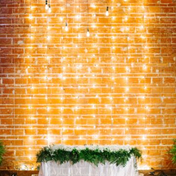 Modern, Romantic Reception and Florida Wedding Decor, Sweetheart Table, with Babies Breath Garland Florals, String light Backdrop on Exposed Brick Wall | | Tampa Bay Premier Wedding Venue NOVA 535 in Downtown St. Pete