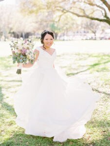 Bride in off the shoulder gown and tiara with white and purple bouquet